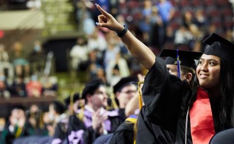 A student points to the crowd during the 187th Commencement ceremony at the Cross Insurance Arena in Portland